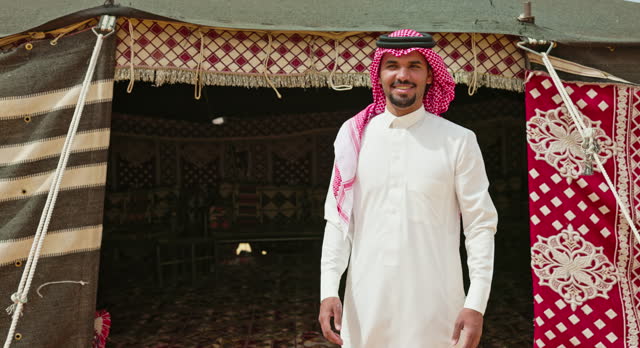 Young Saudi man gesturing to enter shady tent in Al-Ula