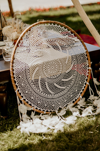 The dreamcatcher gently sways in the breeze, captured in a close-up shot with a soft focus.