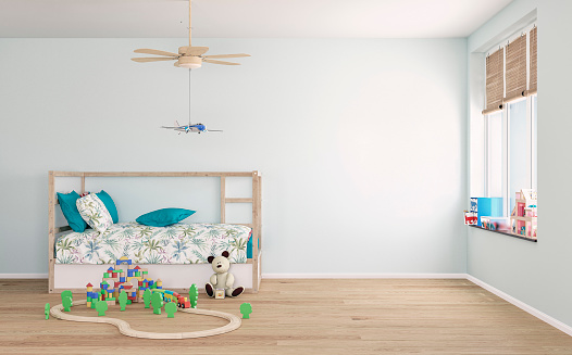 Semi-furnished children Scandinavian style bedroom with a house-shaped canopy bed, a hanging airplane toy from a ceiling fan light, and toys on the hardwood parquet floor (wooden blocks, train set with track, a teddy bear) in front of a pastel mint wall background with copy space. A lot of toys placed on the window sill, a large window with raised bamboo blinds. A 3D rendered image.