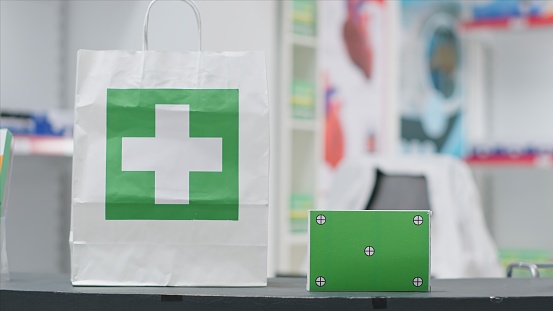 Medical supplies bag with pills and greenscreen shown on box at cash register in pharmacy. Empty drugstore retail shop selling medicine next to pack with isolated copyspace layout, chromakey.