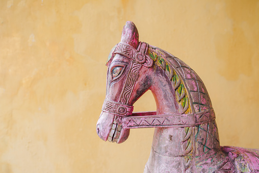 A side statue of a horse on a yellow background.
