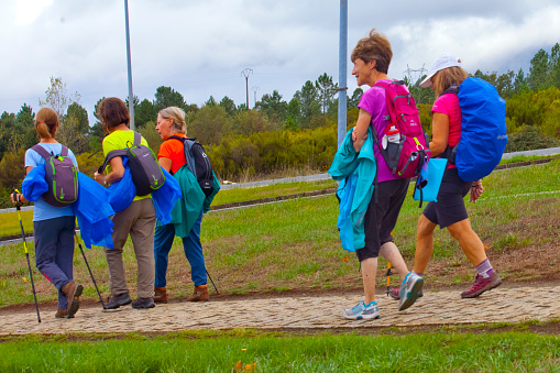 Rear view of group of female pilgrims with backpacks in the 'camino de Santiago' near the city of Santiago de Compostela, Melide, Galicia, Spain. The camino de Santiago is an ancient pilgrimage route which belongs to the UNESCO world heritage.