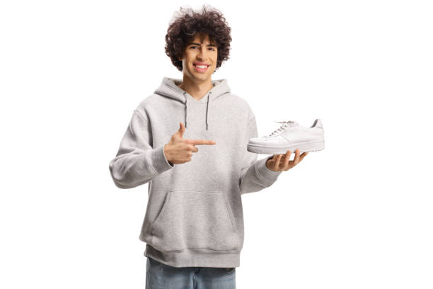 Young man holding a white sneaker and pointing