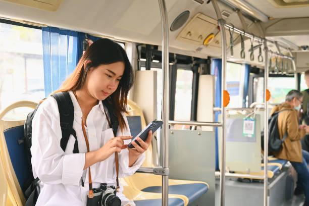 istock Smiling young woman passenger using mobile phone while traveling by bus. Public transportation concept. 1974540368