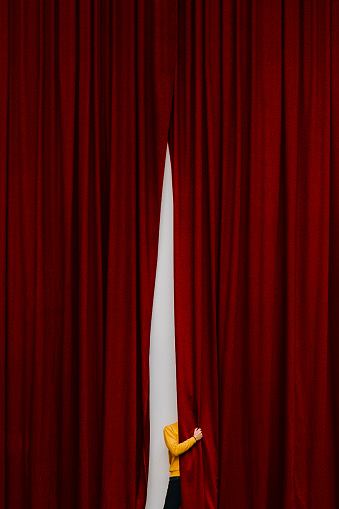 faceless person behind a red theater curtain
