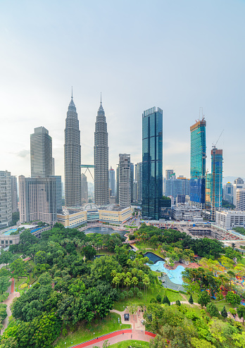 Awesome Kuala Lumpur skyline. Aerial view of a green city park in Kuala Lumpur, Malaysia. Skyscrapers are visible on blue sky background. Kuala Lumpur is a popular tourist destination of Asia.