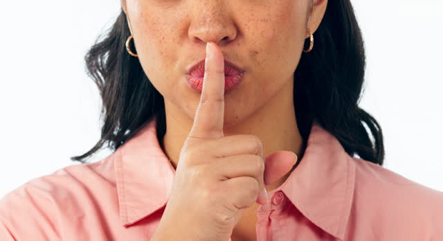 Secret, face and mouth of woman with finger on lips in studio for sign of privacy, confidential mystery or surprise on white background. Closeup, quiet and emoji for gossip, news and voice to whisper