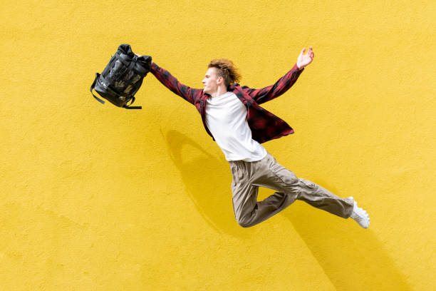 istock young guy student with backpack flies forward and hurries to study, man in superman pose jumps and runs in the air 1974637730