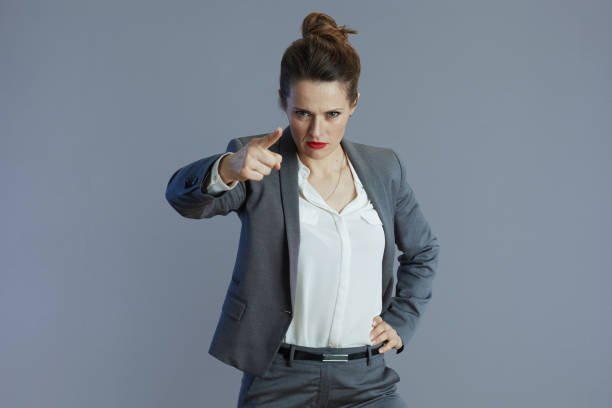 istock fury woman employee threatening with finger isolated on gray 1974658910