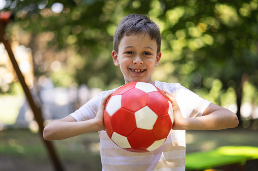 Happy kid holding red soccer ball