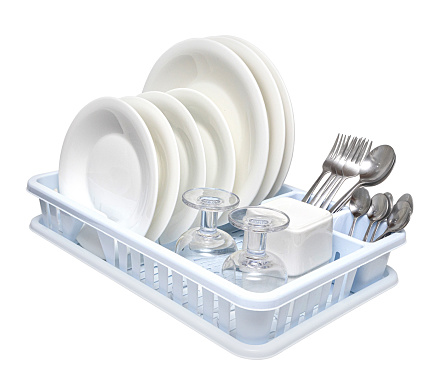 Dish drainer with clean dinnerware on table in kitchen.  With clipping path