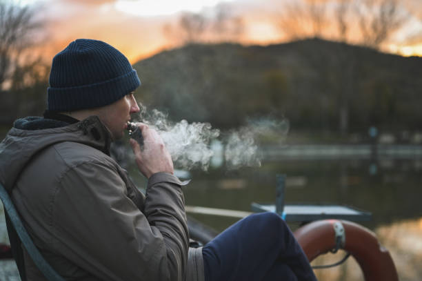 ヒップスターの男は電子タバコを吸う。 - quit lake ストックフォトと画像