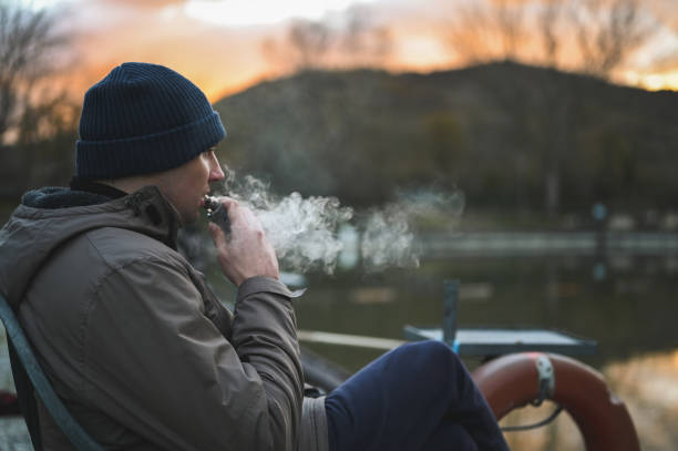 homem hipster fuma um cigarro eletrônico. - quit lake - fotografias e filmes do acervo