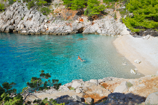 Lonely swimming woman in the sea in beautiful turquoise bay