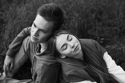 young teen couple laying on a grass on a field in september