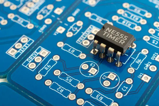 Photo of NE555 timer integrated circuit on a blue pcb