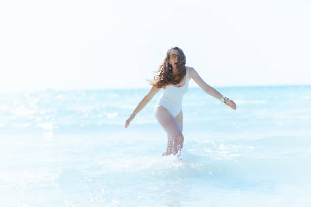 istock smiling modern female on beach having fun time in water 1974708019