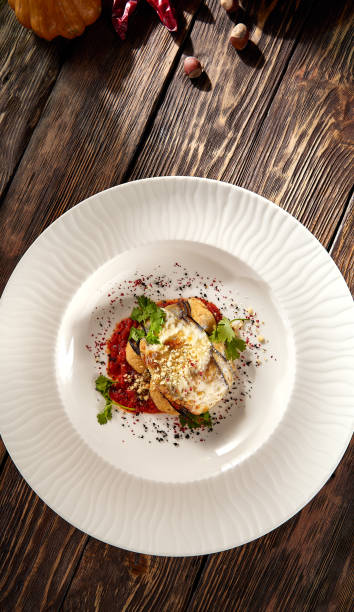 istock Baked eggplant roll filled with cheese and tomatoes, presented on a pristine white plate, top view 1974735670