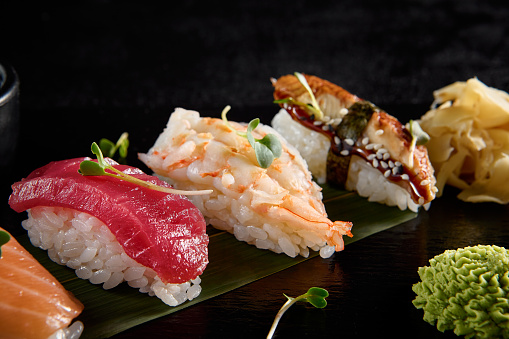 Classic nigiri sushi with salmon, tuna, eel, and shrimp on a black slate.