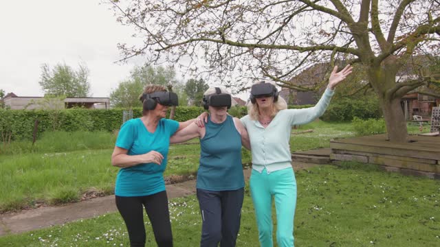Three elderly women appear shocked and happily amazed as they try on virtual reality glasses