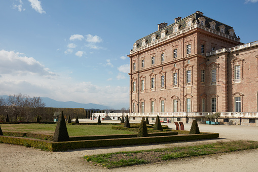 Reggia di Venaria castle architecture and park with pyramidal hedges in spring sunlight