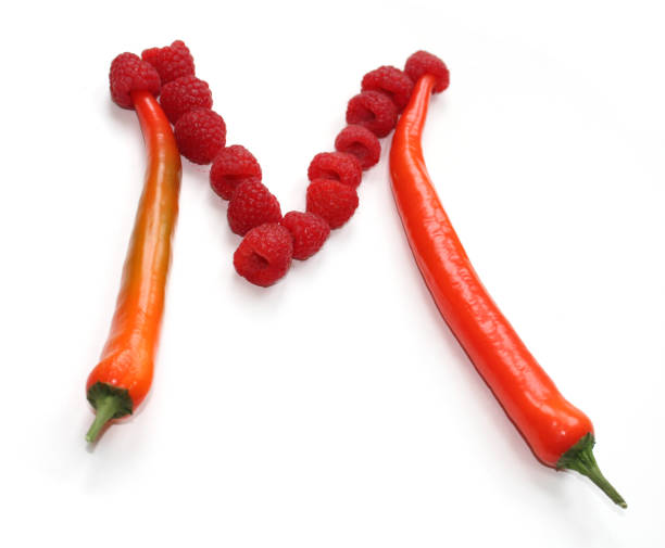 istock Letter M made from orange chili pepper and red raspberry, vegetable letters 1974790077