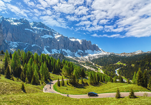 Immerse yourself in the awe-inspiring beauty of the Dolomites, a picturesque landscape in the heart of the European Alps. This captivating photo showcases the rugged beauty of the mountain peaks, the winding roads carving through the majestic scenery, and the dramatic play of sunlight filtering through the clouds.