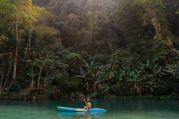 istock Man canoeing in blue lagoon surrounded by tropical rainforest 1974810791
