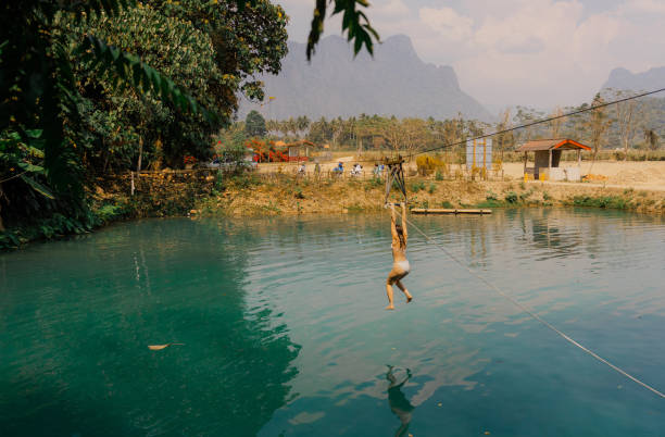 istock Woman jumping into the water from a rope swing in tropical setting 1974811045