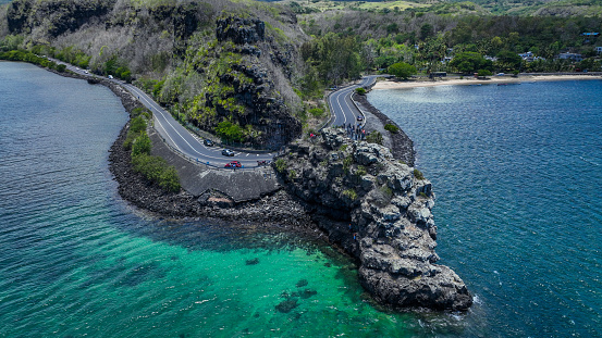An aerial photograph captures a road winding along the side of a cliff in beautiful Mauritius.