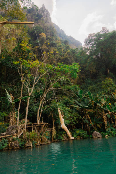 istock Woman jumping into the water from a rope swing in tropical setting 1974831013