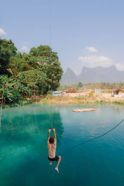 istock Man jumping into the lagoon from rope swing 1974835386