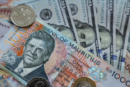 A stack of money with a single penny placed on the top, showcasing the currency of Mauritius.