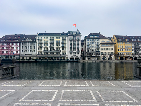 Historical buildings on riverbank of Reuss river. Copy space. Swiss flag.