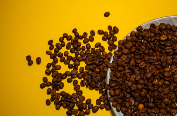 istock Coffee beans isolated on the yellow background. Joyful minimal coffee-theme with copy space 1974848867