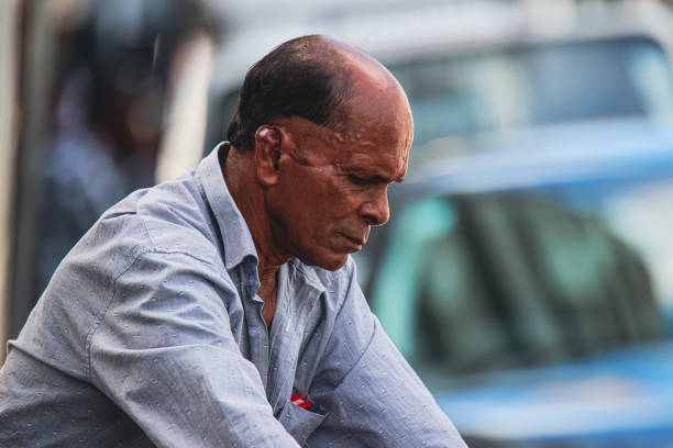 Port Louis, Mauritius - January 12, 2023: A local man is sitting on a bench in Mauritius, with his hands resting on his knees.