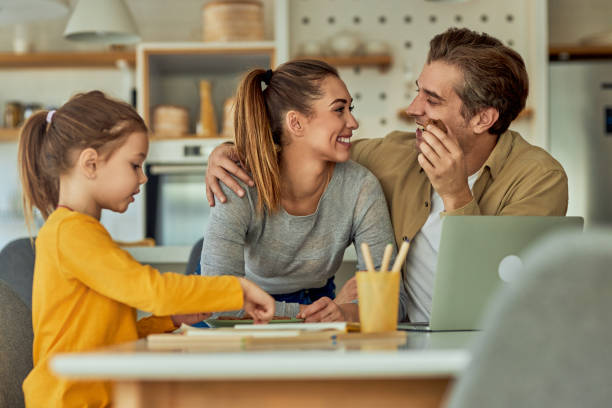 istock Husband and wife look at each other while their daughter is drawing, in the kitchen. 1974875759