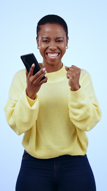 African woman, phone and celebration in studio for trading success, profit or wow by blue background. Excited, winner girl, smartphone and cheers for prize or lotto with revenue, portrait or loan