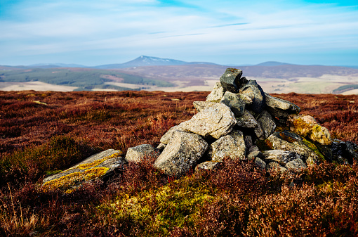 Small rock cairn on the summit of a hill in Aberdeenshire, Scotland. The hill in the background is Ben Rinnes.