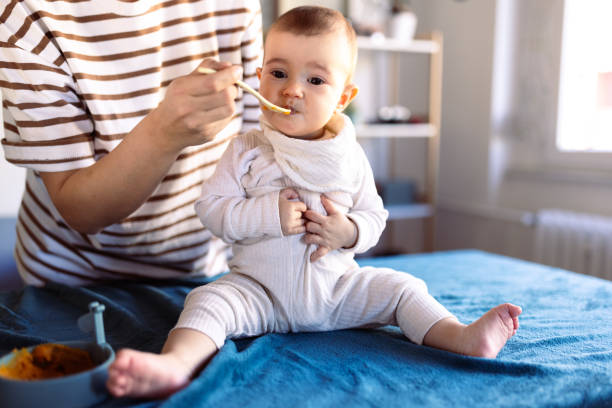 istock Cute baby trying her first solid food at home 1974924213
