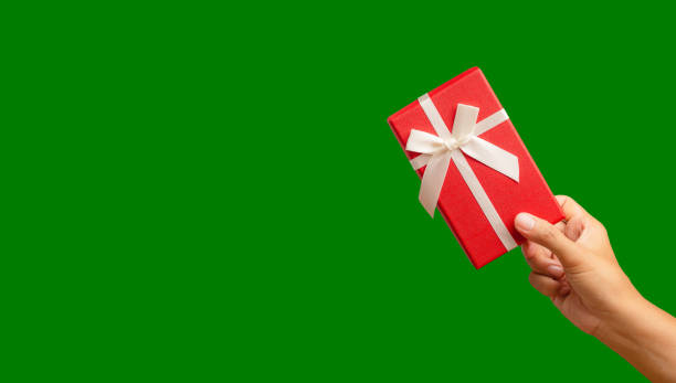 istock Hand holding of a red gift box against a green background. 1974929017