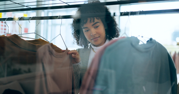 Shopping, fashion and woman thinking in a mall for clothes, search or outfit choice. Retail, deal and female customer check fabric, texture or quality in a thrift store for discount, sale or decision