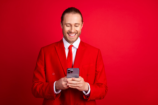 Photo portrait of handsome young guy hold device eshopping wear trendy classic outfit isolated on red color background.