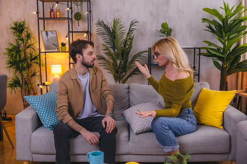 Young heterosexual couple fighting in the living room.