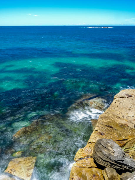 istock Powerful white swirling waves (blurred motion) crashing into coastline rocks 1974977423