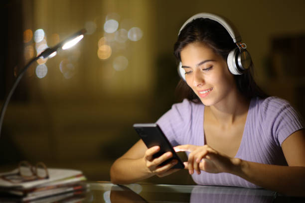 istock Happy woman in the night using phone weraring headphone 1974997673