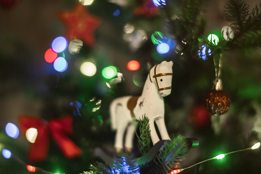 Christmas tree with horse decoration and lights background, close-up.