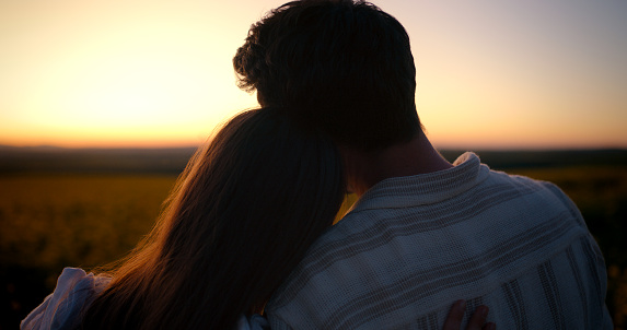 Sunset view, love and silhouette of couple relax in outdoor countryside for support, care and wellness on romantic date. Nature, dark shadow and back of man, woman or people bonding on Valentines Day