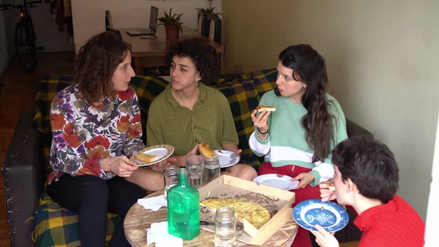 Female friends talking and eating pizza at home