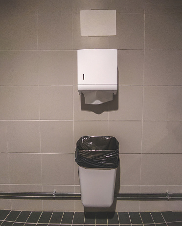 Plastic box for paper towels and trash can in a public toilet. Hygiene and cleanliness.